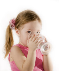 Small girl is drinking the water from a glass